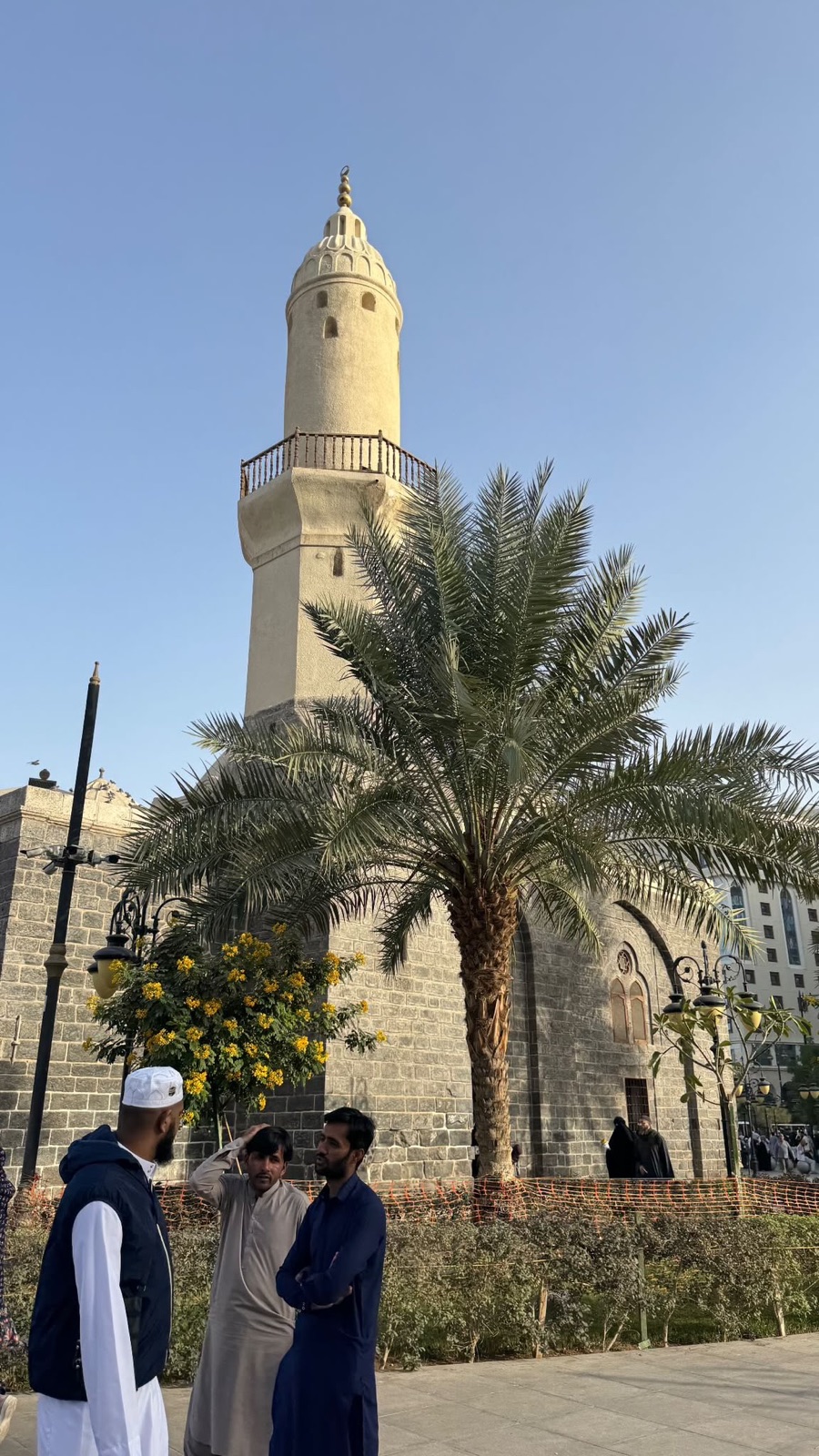 De minaret van de Quba-moskee in Medina met een dadelpalm ervoor