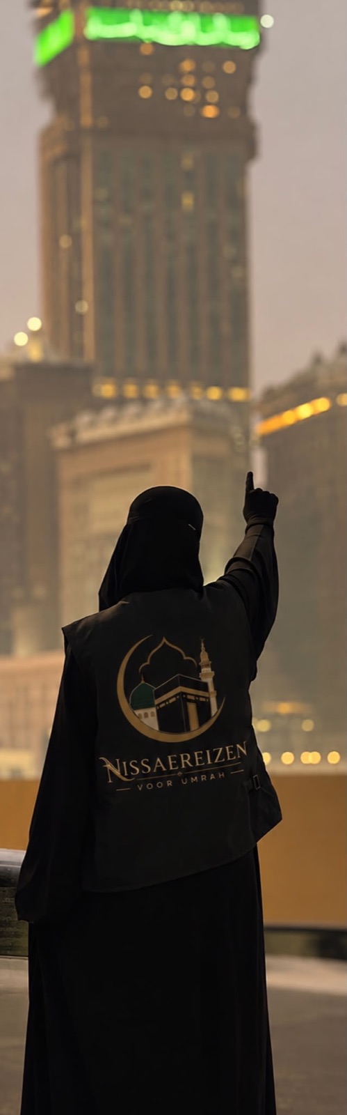 Een zuster in een jas van Nissae Reizen kijkt omhoog in Mekka